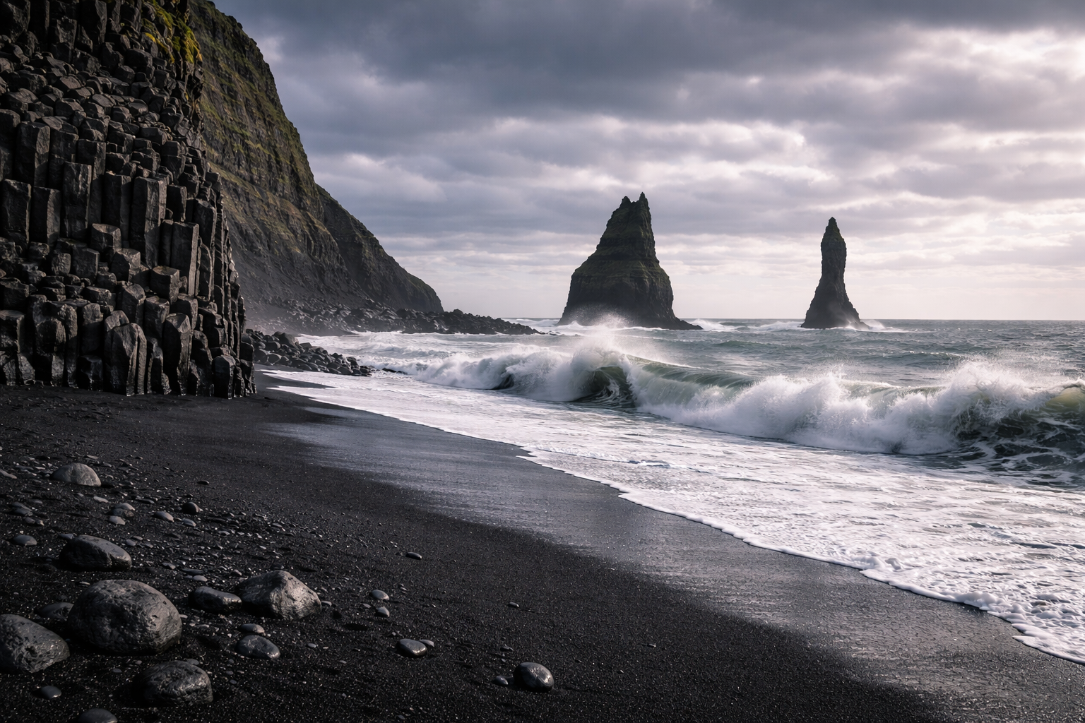Reynisfjara pludmale Islandē ar melnām smiltīm, bazalta kolonnām, okeāna viļņiem un klintīm ūdenī