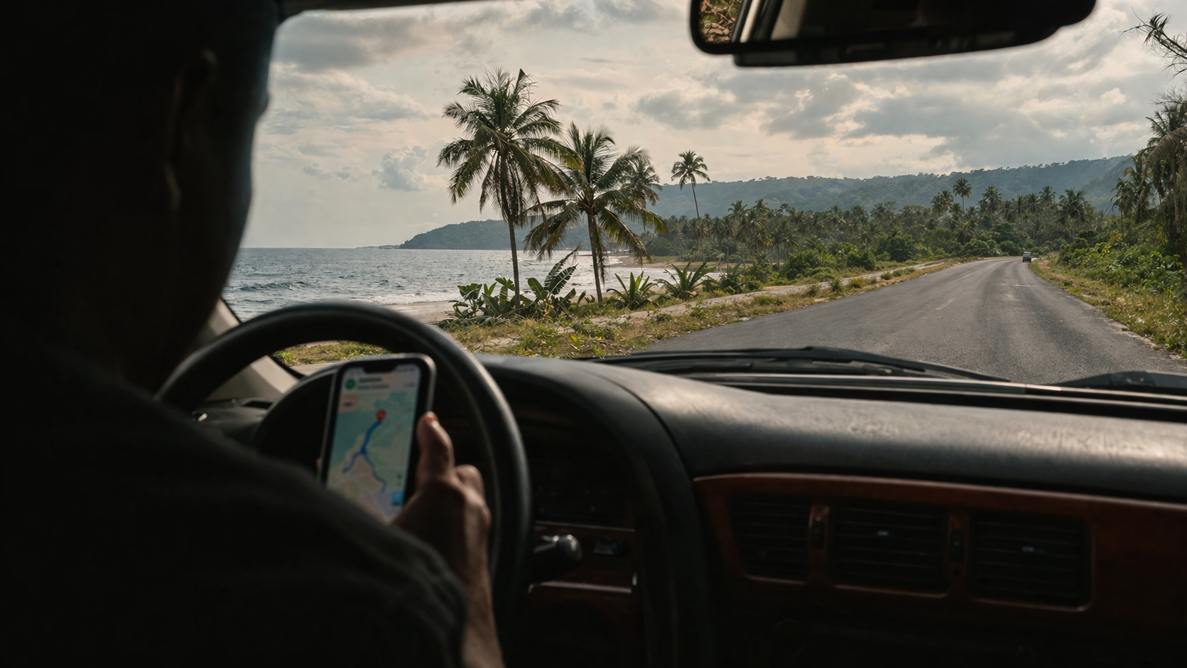 Kelias palei pakrantę ir keliautojas, žiūrintis maršrutą telefone