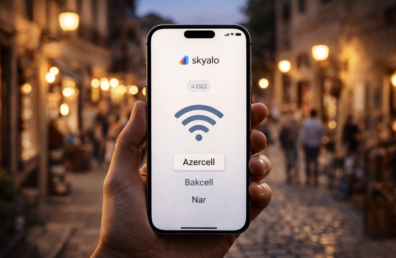 Close-up of a hand holding a modern smartphone with the Skyalo app on screen—logo, eSIM icon, Wi‑Fi symbol, and a list of networks: Azercell, Bakcell, and Nar; in the background, the evening streets of Icherisheher in Baku with warm lights and soft bokeh.