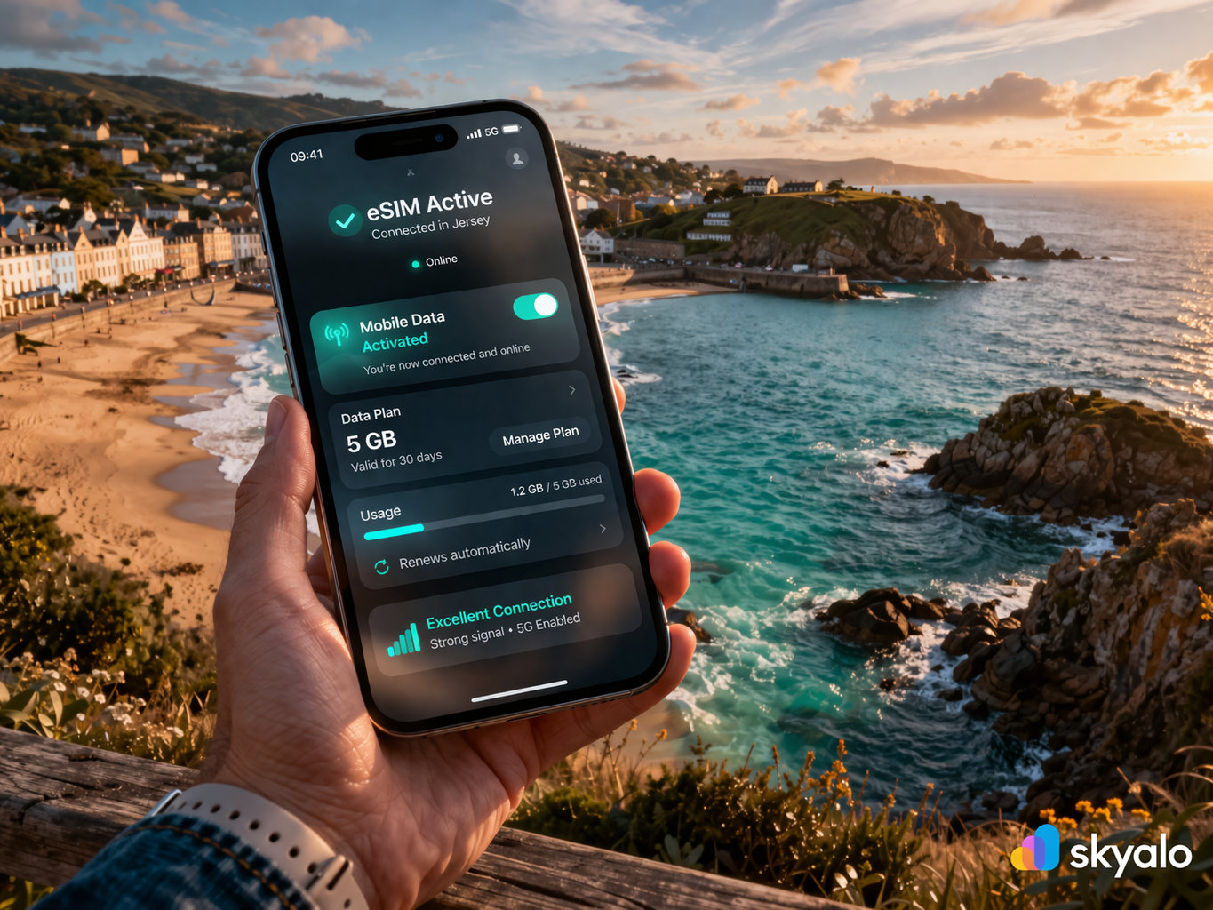 סמארטפון עם eSIM פעילה ואינטרנט סלולרי עובד על רקע נופי החוף היפים של ג'רזי, הים, החוף והצוקים.