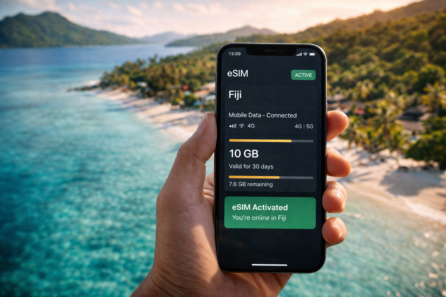 Smartphone s aktivovanou eSIM pro Fidži na obrazovce na pozadí tropické pláže s palmami a oceánem