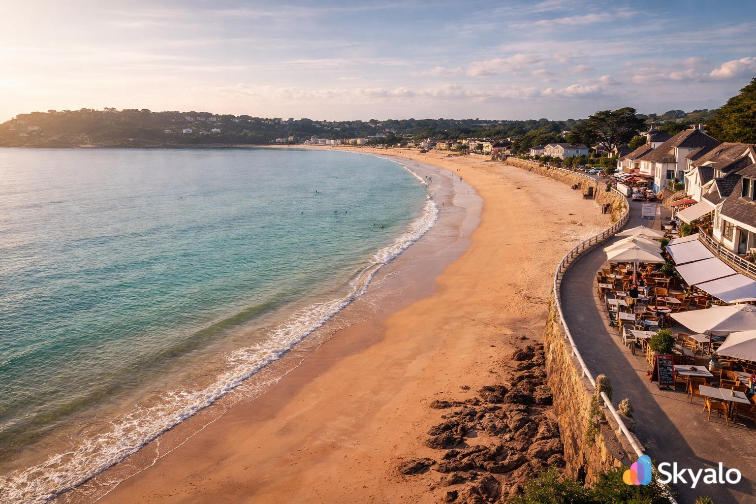 מפרץ סנט ברלייד'ס בג'רזי עם חוף חול רחב, מים שקטים, טיילת ואור שמש רך.